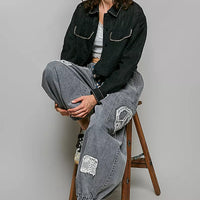 Black cropped button-front eyelet cotton jacket with contrast topstitching, worn with gray pants.