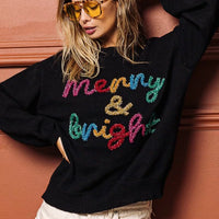 Black sweater with multicolor tinsel "Merry & bright" lettering, loose long sleeves.