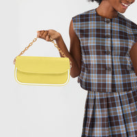 Yellow leather shoulder bag with gold chain strap and front flap, held in hand.