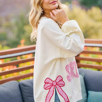 Cream sweatshirt with red bow patch, star detail, and striped graphic