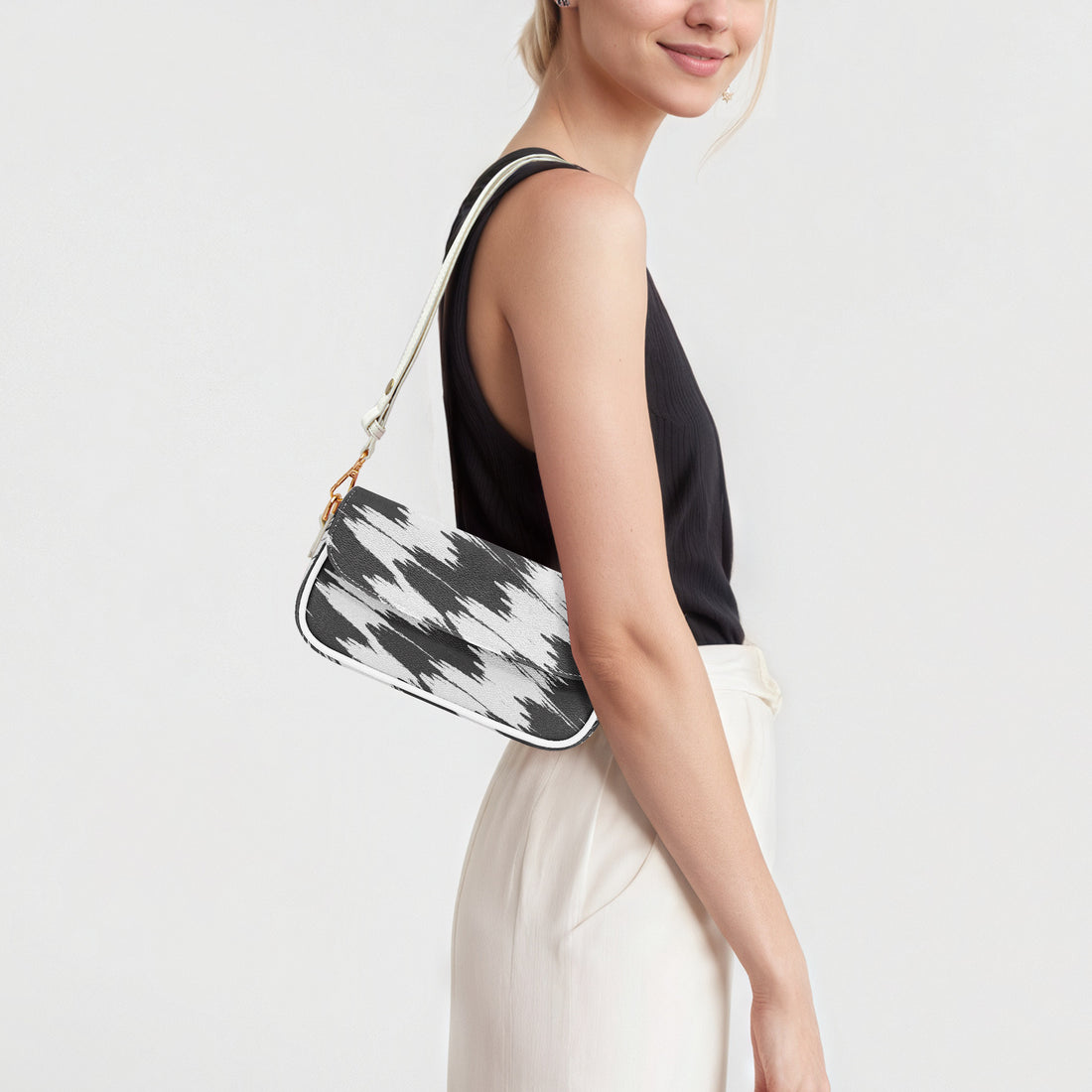 Black and white cowprint shoulder bag side view with white strap and gold chain