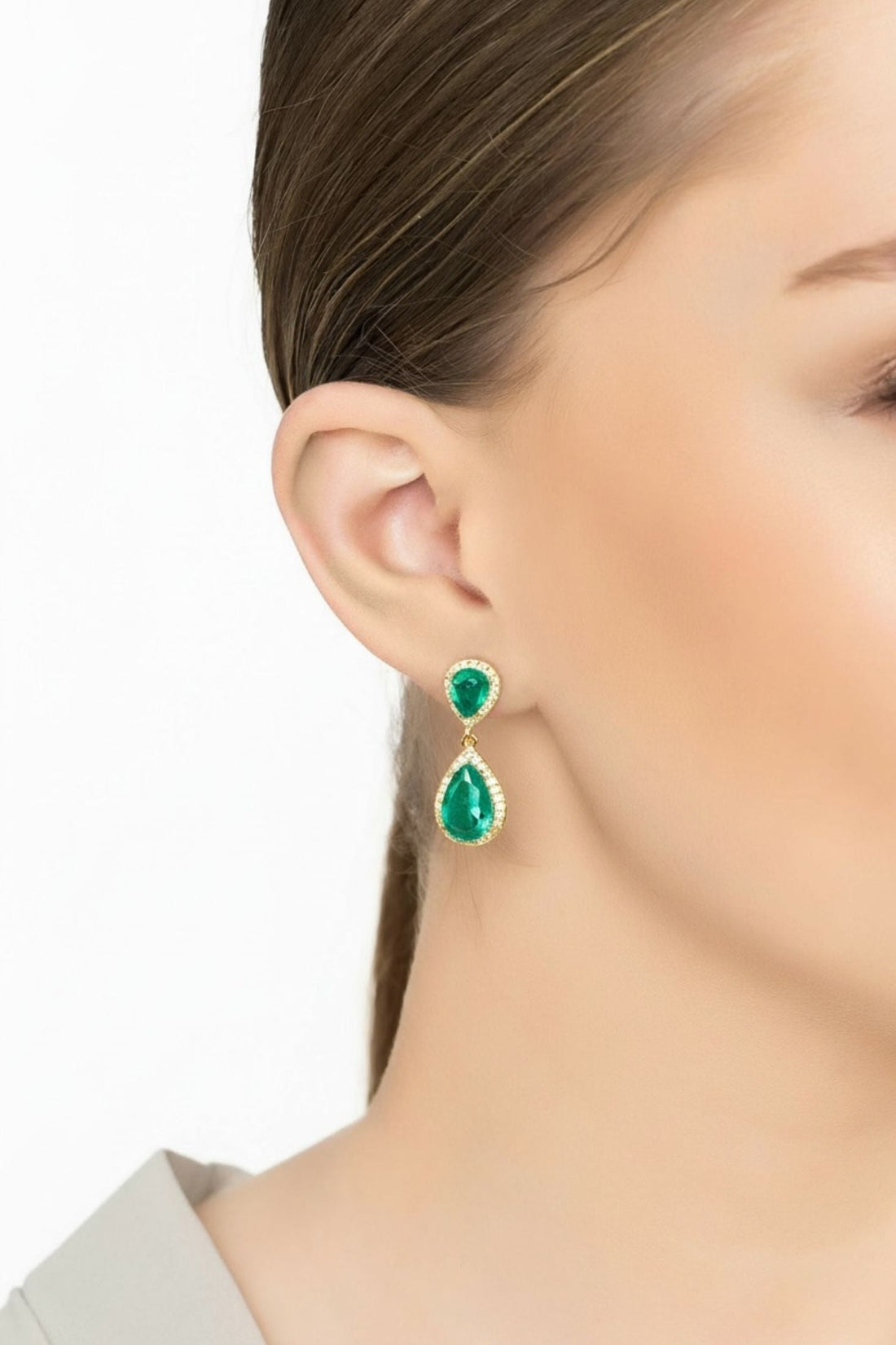 Emerald-green teardrop drop earrings on gold hooks, worn by model