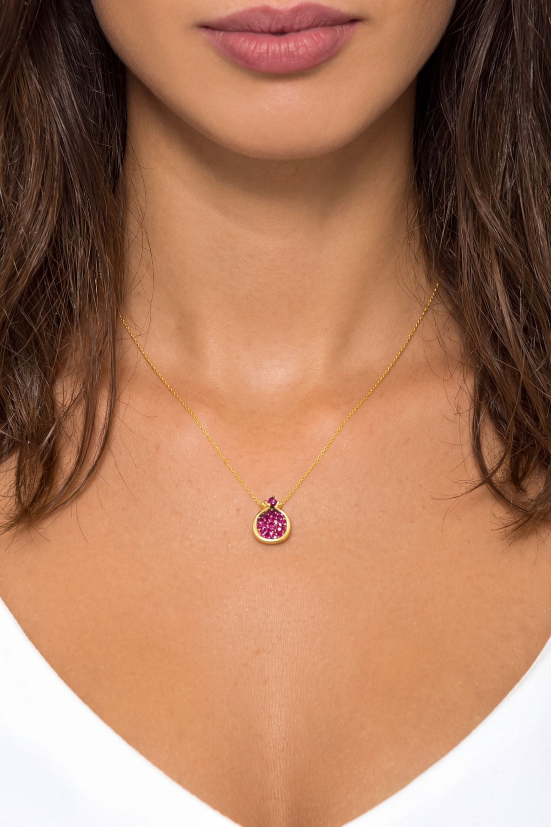 Gold pendant necklace with ruby-pink crystal-set pomegranate charm centered at neckline