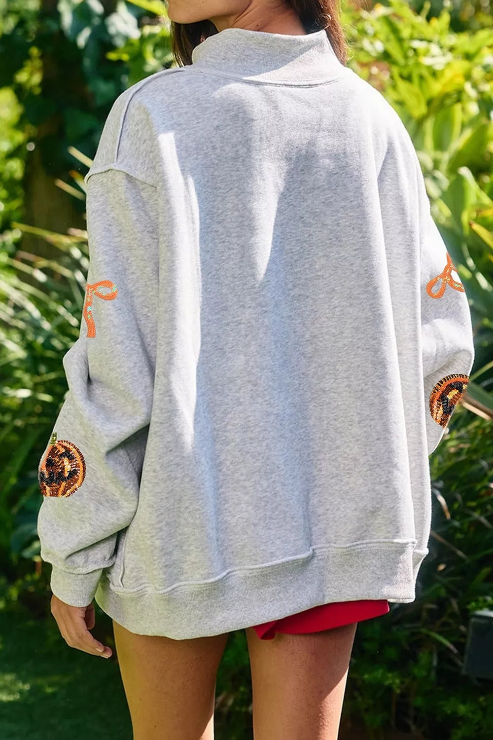 Light gray Halloween sweatshirt back view with orange pumpkin and bow motifs