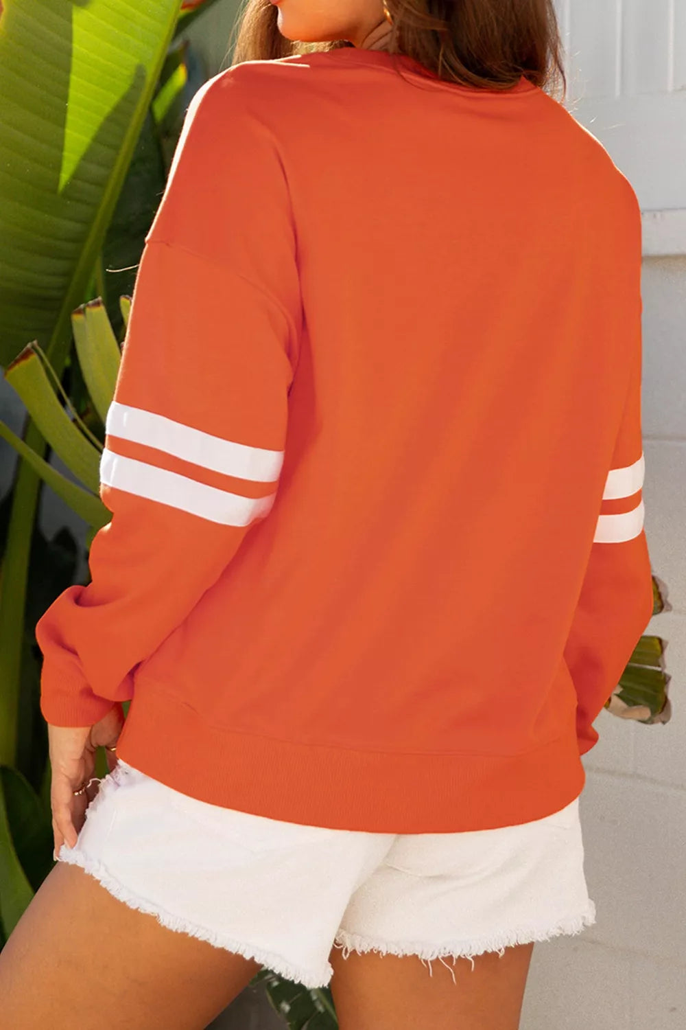 Orange sweatshirt back view with white striped sleeve bands