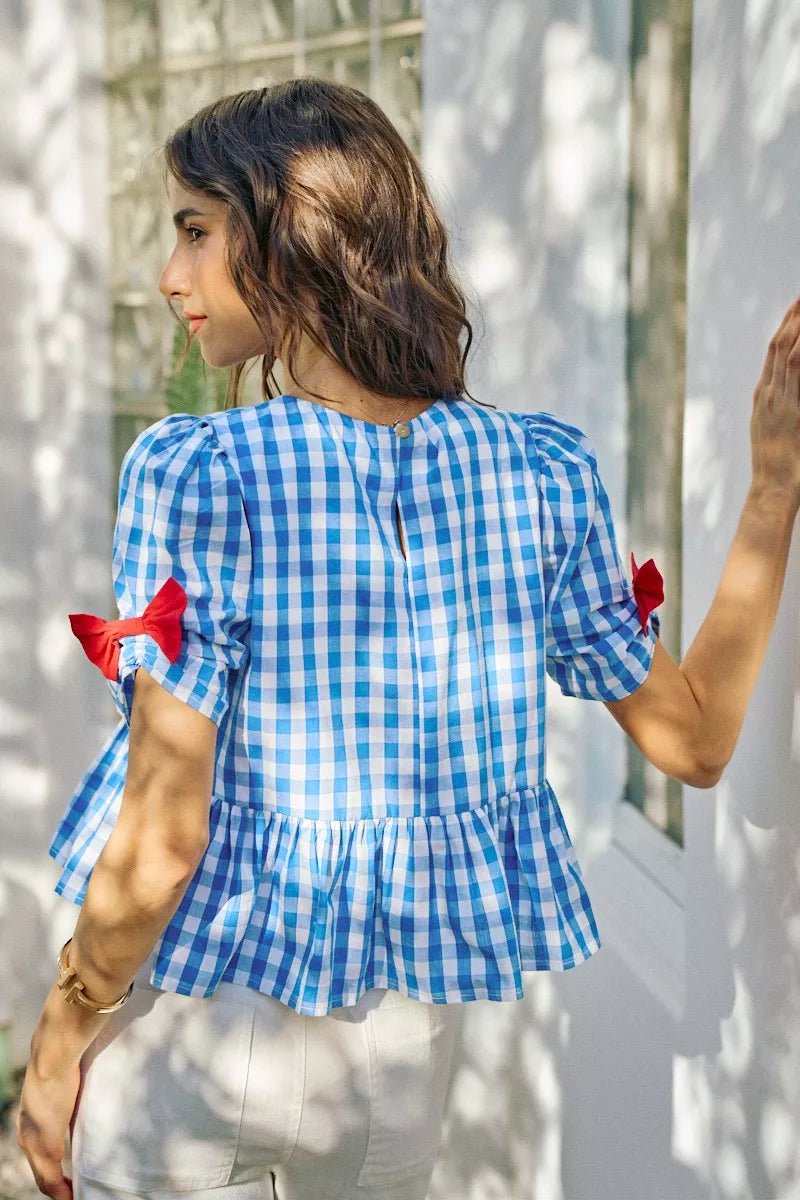 Blue gingham short-sleeve peplum blouse with gathered back and red bow details