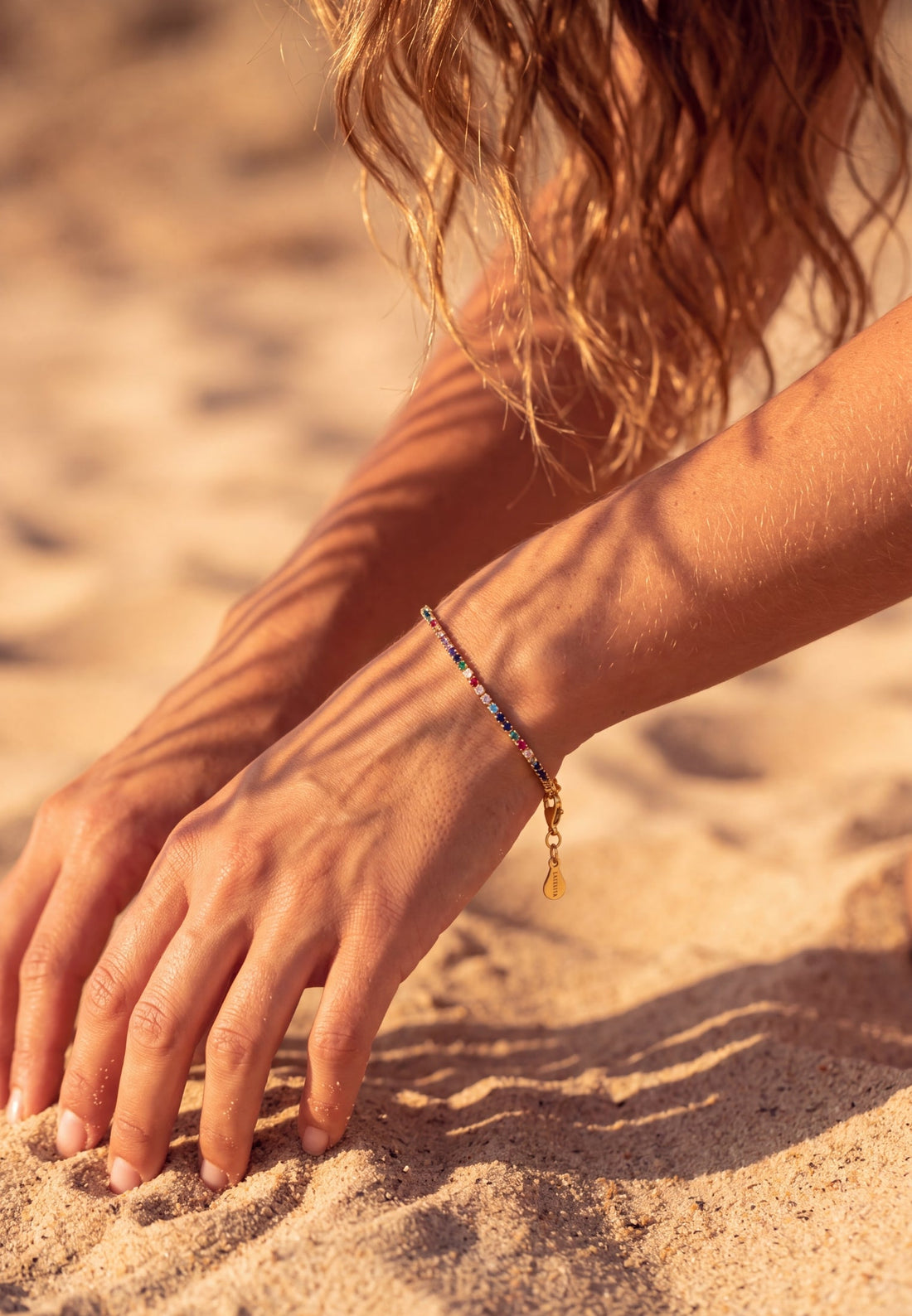 Rainbow CZ tennis bracelet on wrist with gold heart toggle clasp