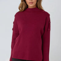 Wine red high-neck jumper with buttoned shoulder details and long sleeves