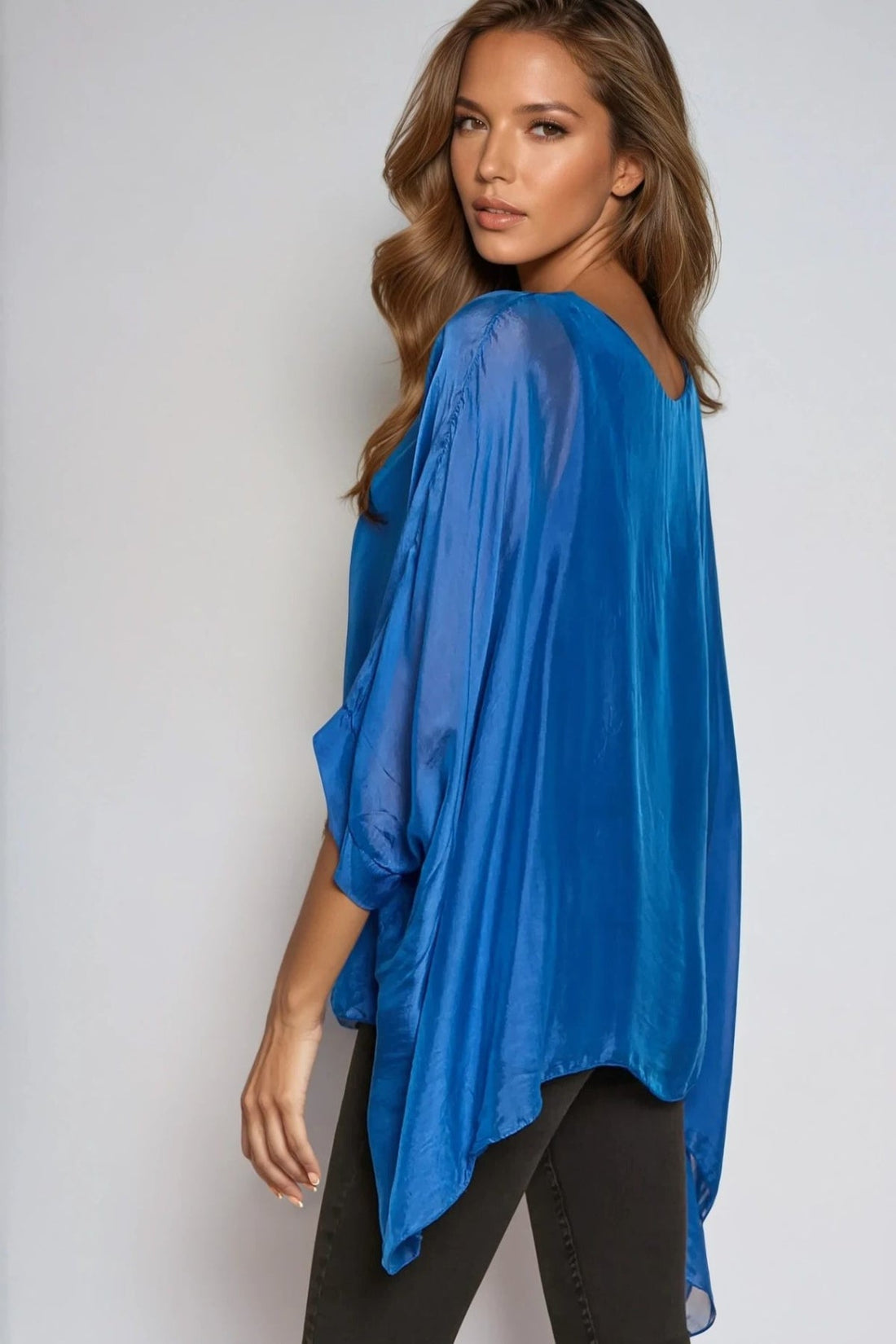 Royal blue silk blouse with round neck and batwing sleeves, angled side view drape.