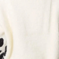 Ivory knit jumper fabric close-up with soft ribbed texture and black motif edge