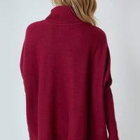 Burgundy roll-neck poncho jumper with ribbed collar in a relaxed back view