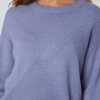 Denim blue knit jumper close-up with round crew neck and geometric diamond stitch