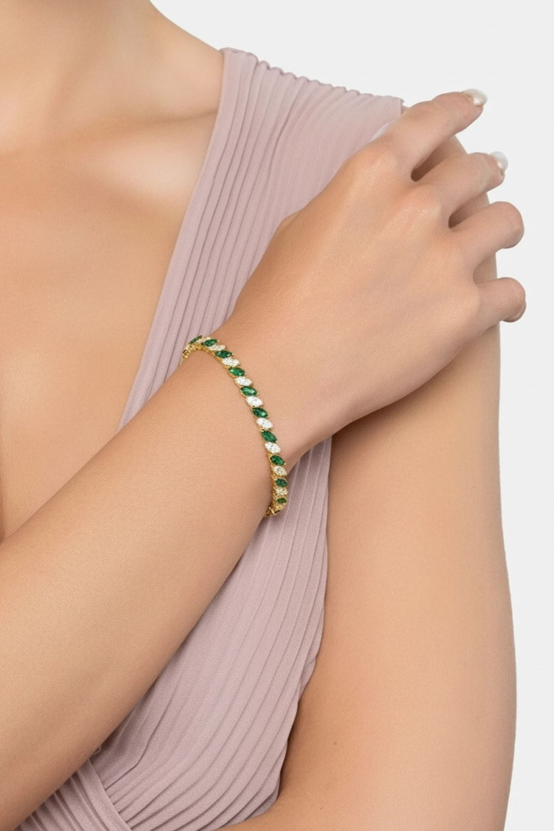 Emerald-green stone tennis bracelet on wrist with gold setting and links