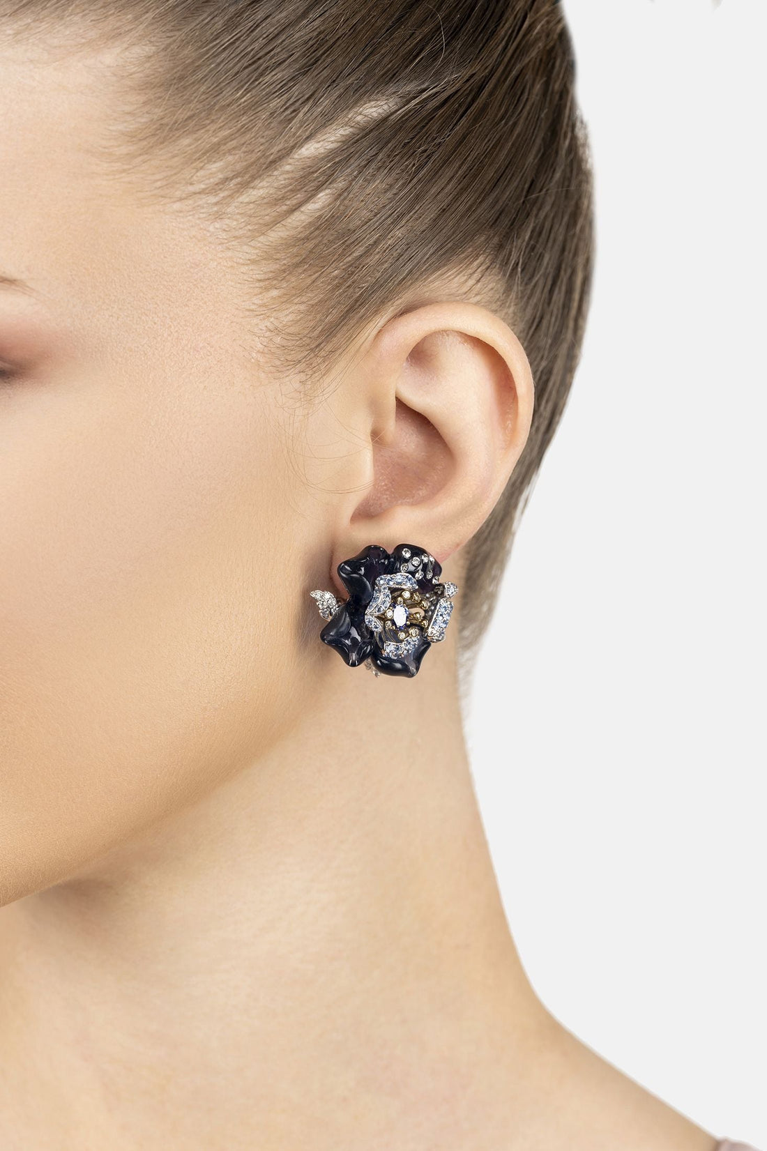 Blue enamel flower stud earrings on ear, with gold center and crystal accents