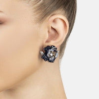 Blue enamel flower stud earrings on ear, with gold center and crystal accents
