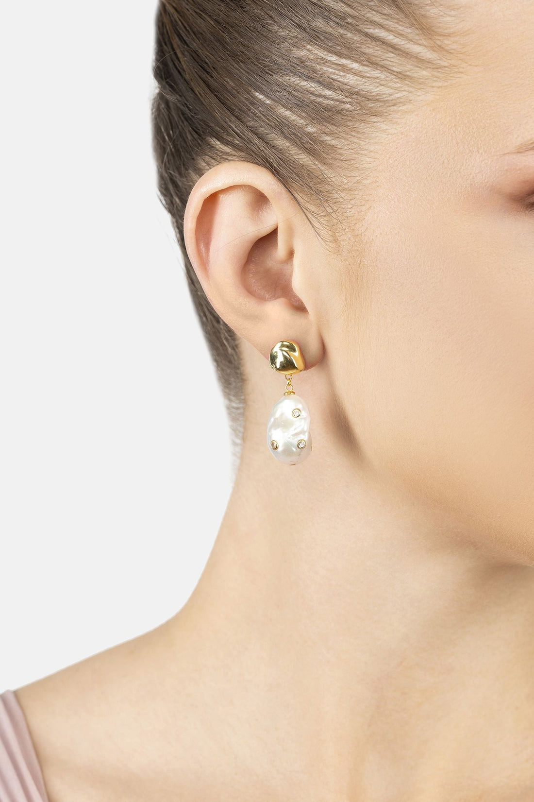 Gold-tone teardrop pearl drop earrings with baroque studs on the ear