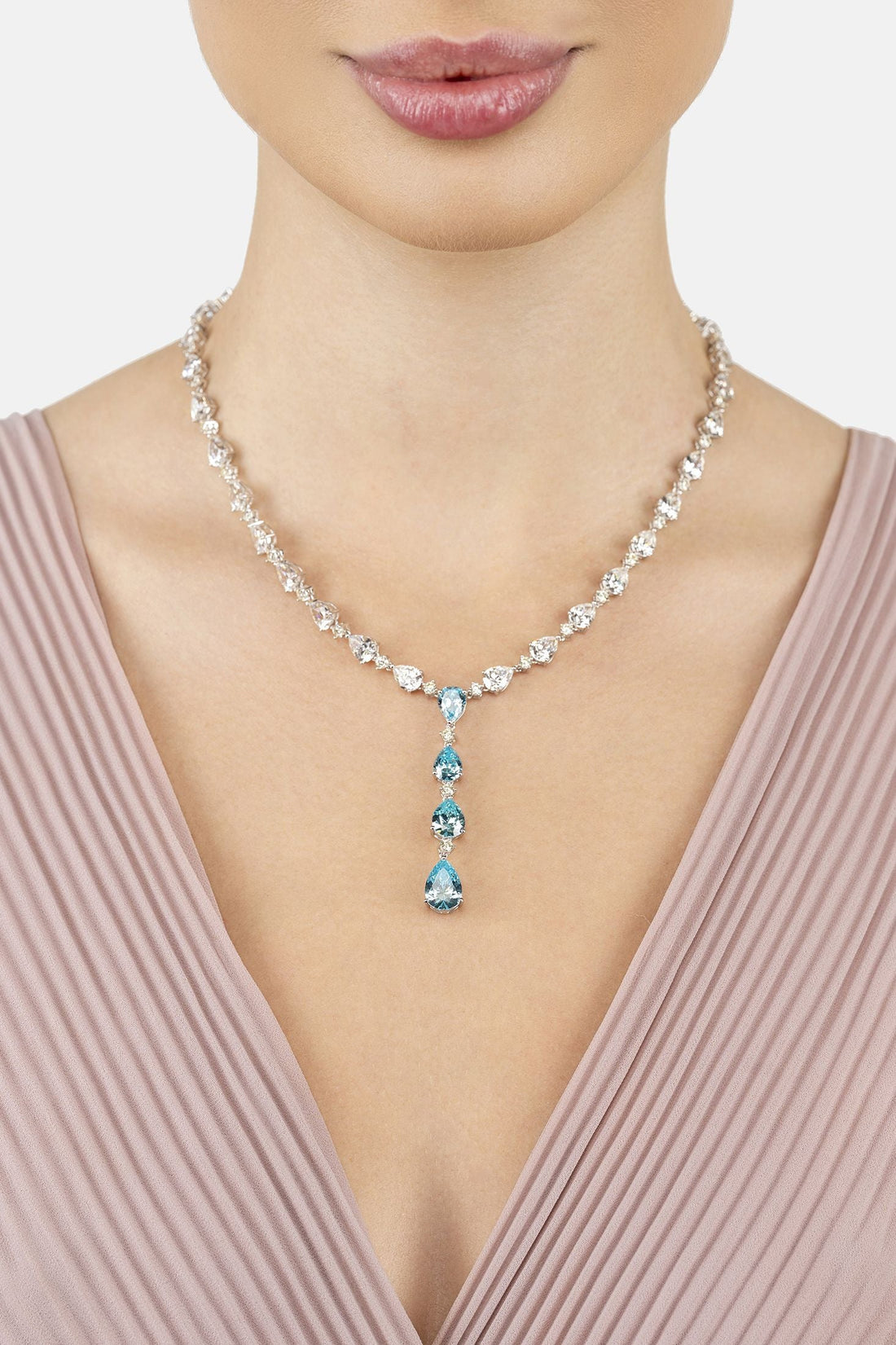 Silver necklace with blue drop gemstones and linked clear stones, worn at the neckline