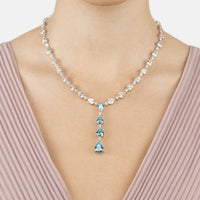 Silver necklace with blue drop gemstones and linked clear stones, worn at the neckline