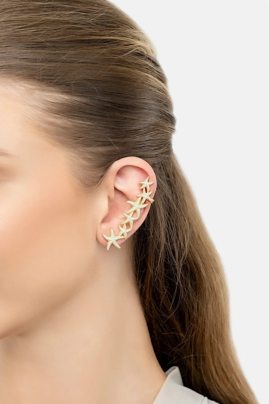 Gold starfish ear climber earring on left ear, close-up of star segments