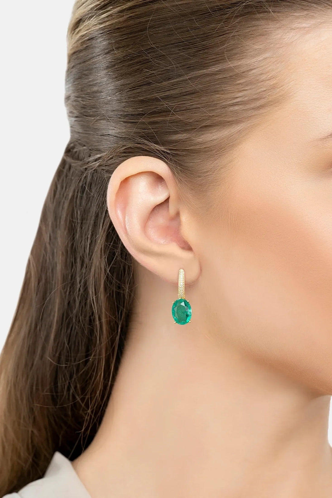 Emerald-green oval drop earring with small gold top detail on model ear