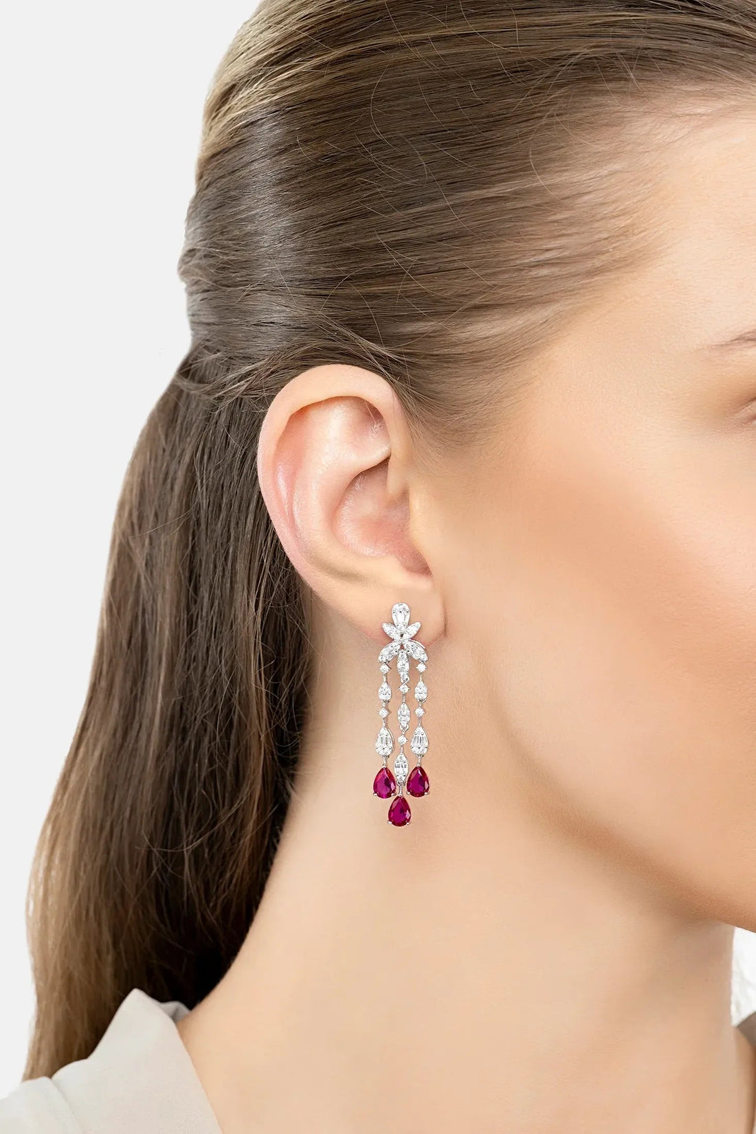 Dangling silver earrings with purple teardrop drops, worn on ear