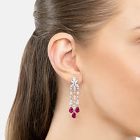 Dangling silver earrings with purple teardrop drops, worn on ear
