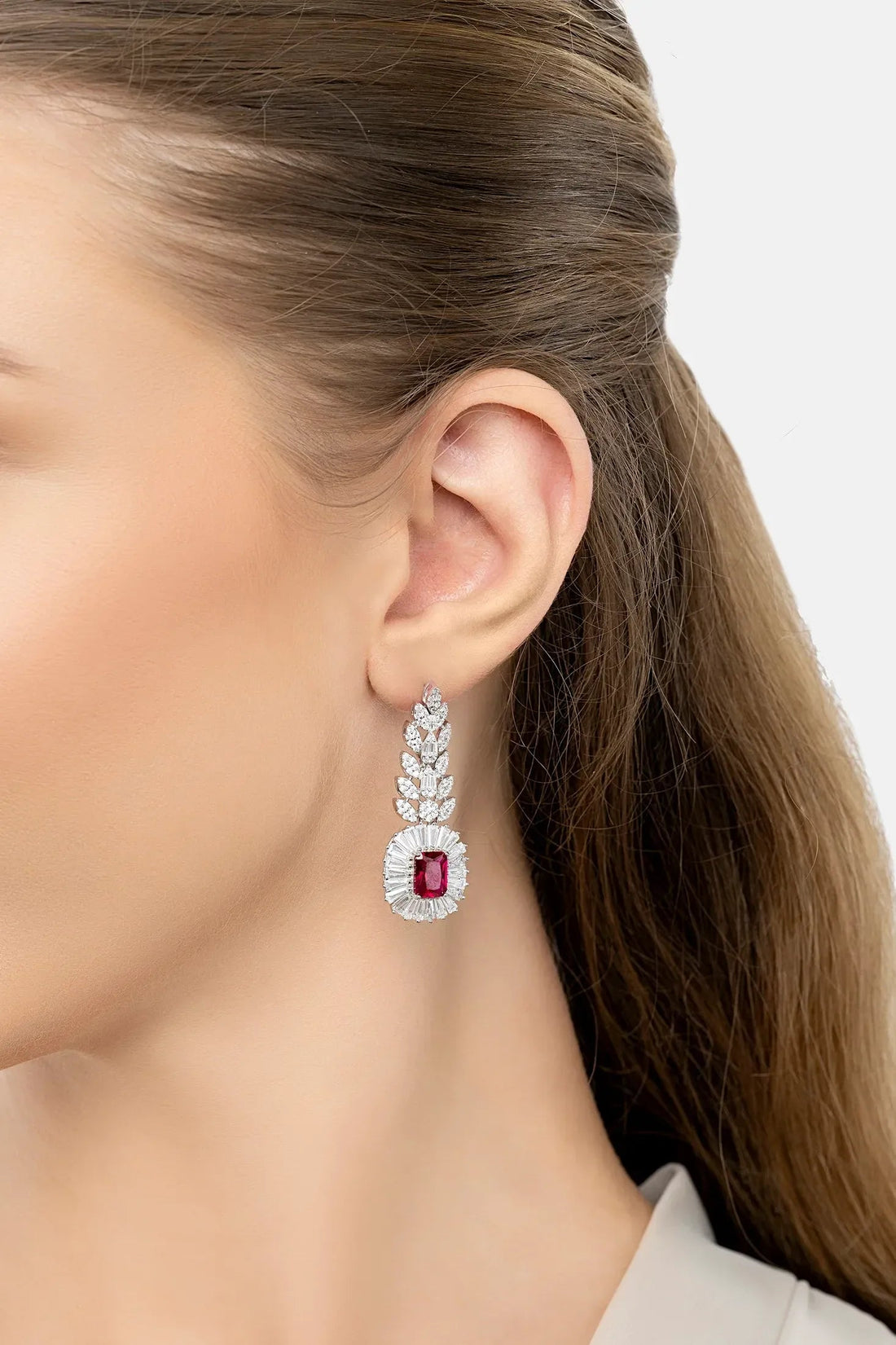 Gemstone drop earrings with ruby center in silver, worn on ear