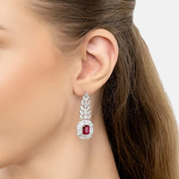 Gemstone drop earrings with ruby center in silver, worn on ear