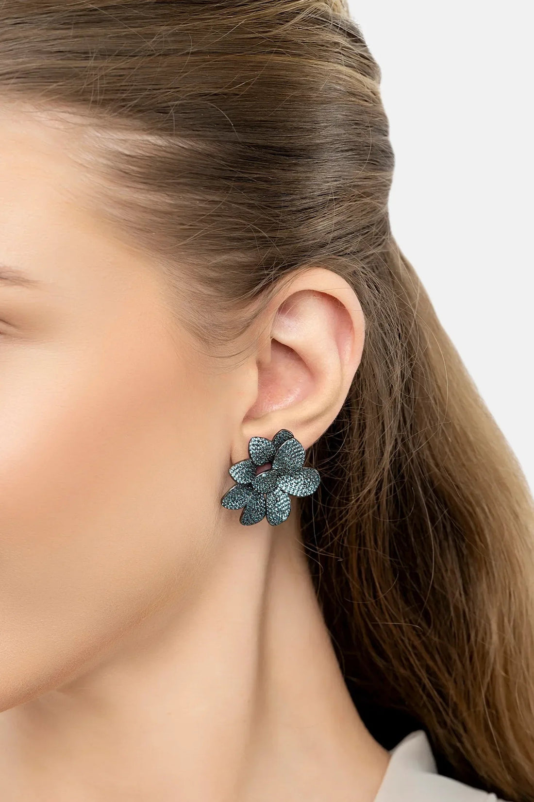 Close-up of large aqua flower stud earrings with sparkling textured petals