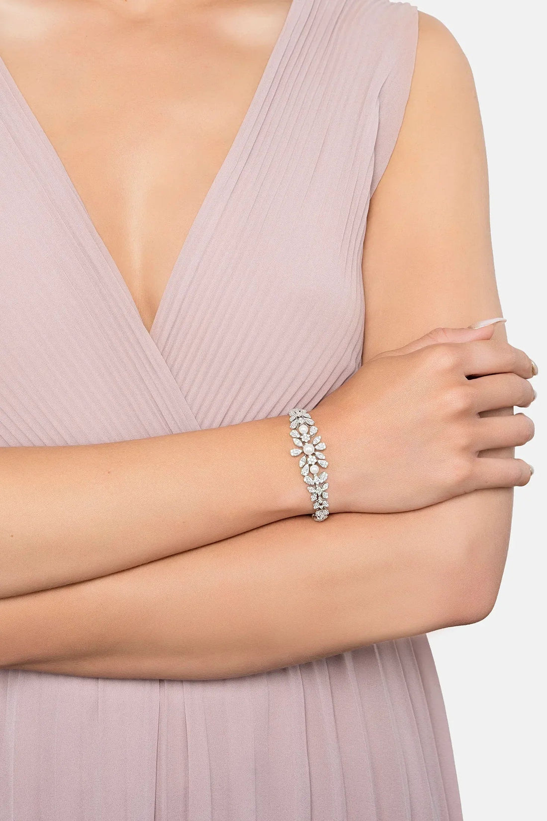 Crystal tennis bracelet with floral leaf design and pearl center on a wrist