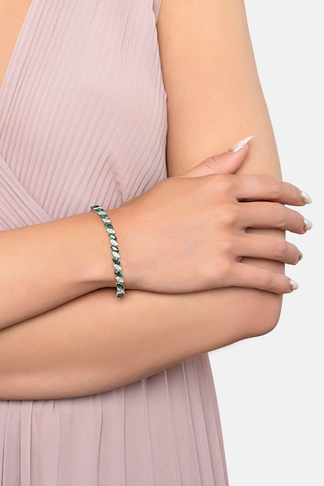 Silver tennis bracelet with emerald-green stones on inner wrist