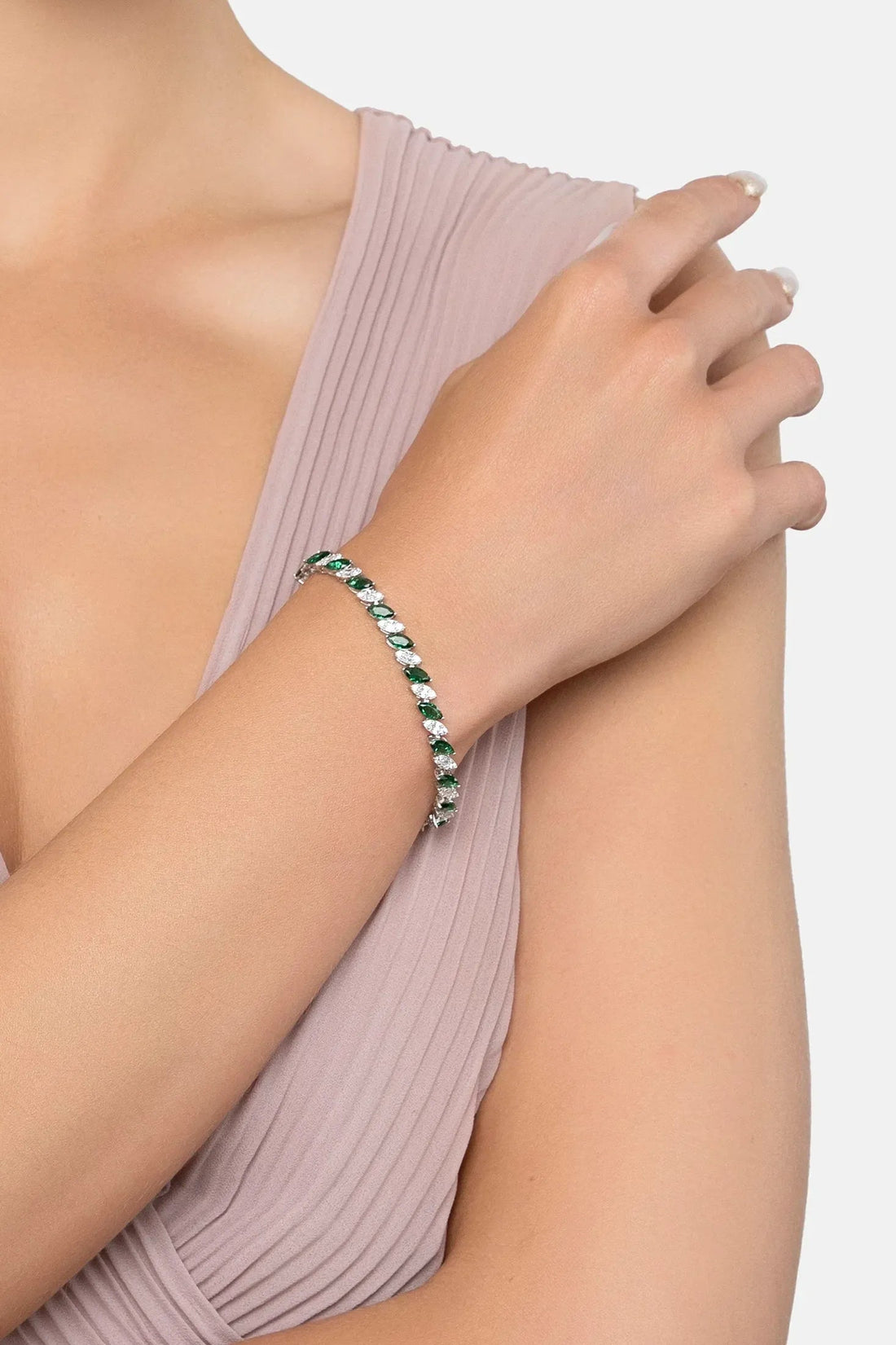 Emerald-green gemstone tennis bracelet on wrist with silver links