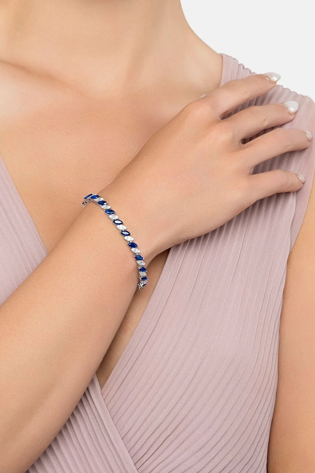Sapphire tennis bracelet on wrist with oval blue stones and silver links