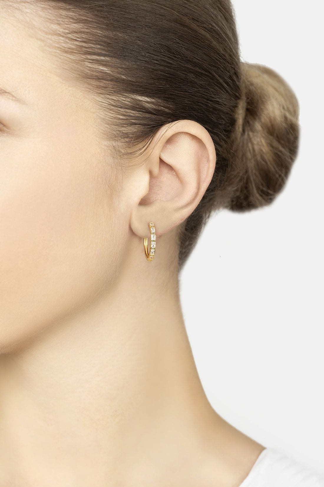 Gold hoop earrings with baguette-cut clear stones, worn on ear