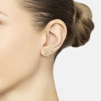 Gold snake stud earring with green eye, worn on ear