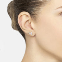 Silver snake stud earrings with green CZ accent, close-up side view on ear