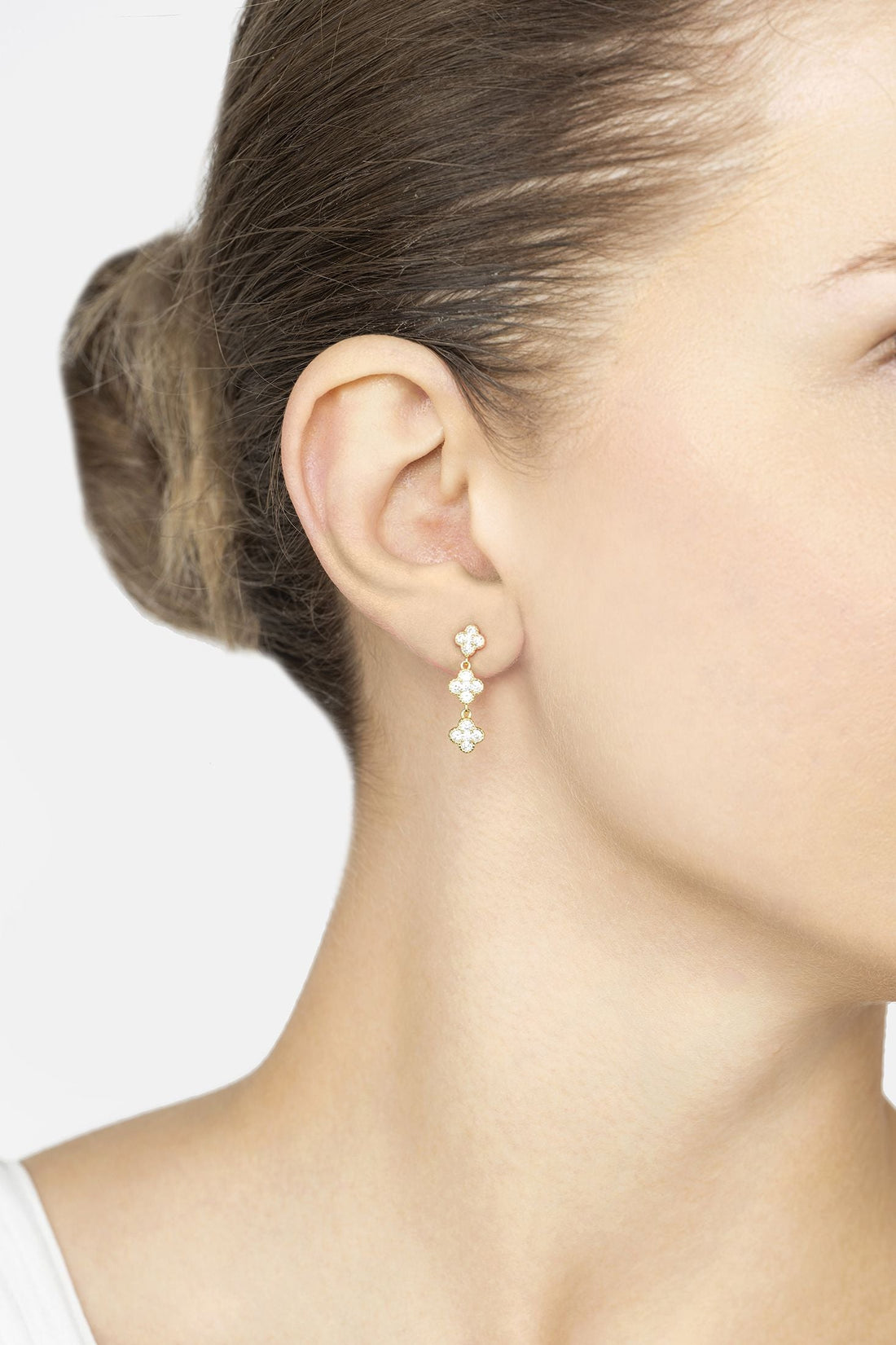 Small gold triple clover drop earrings with crystal sparkle on ear