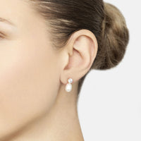 Gold earrings on ear: round sparkle stud with white pearl teardrop drop