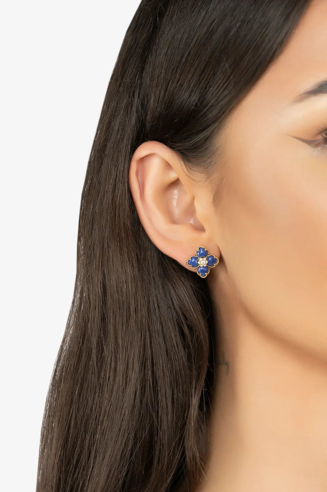 Gold-tone blue clover flower stud earrings on ear