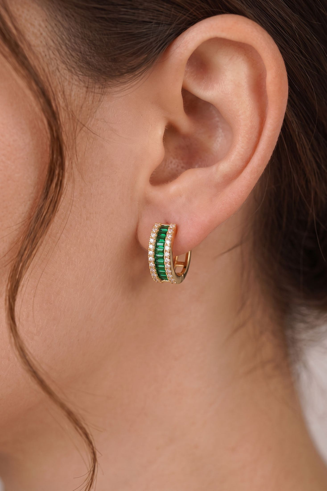 Emerald green baguette huggie hoop earrings with gold posts and crystal sparkle detail