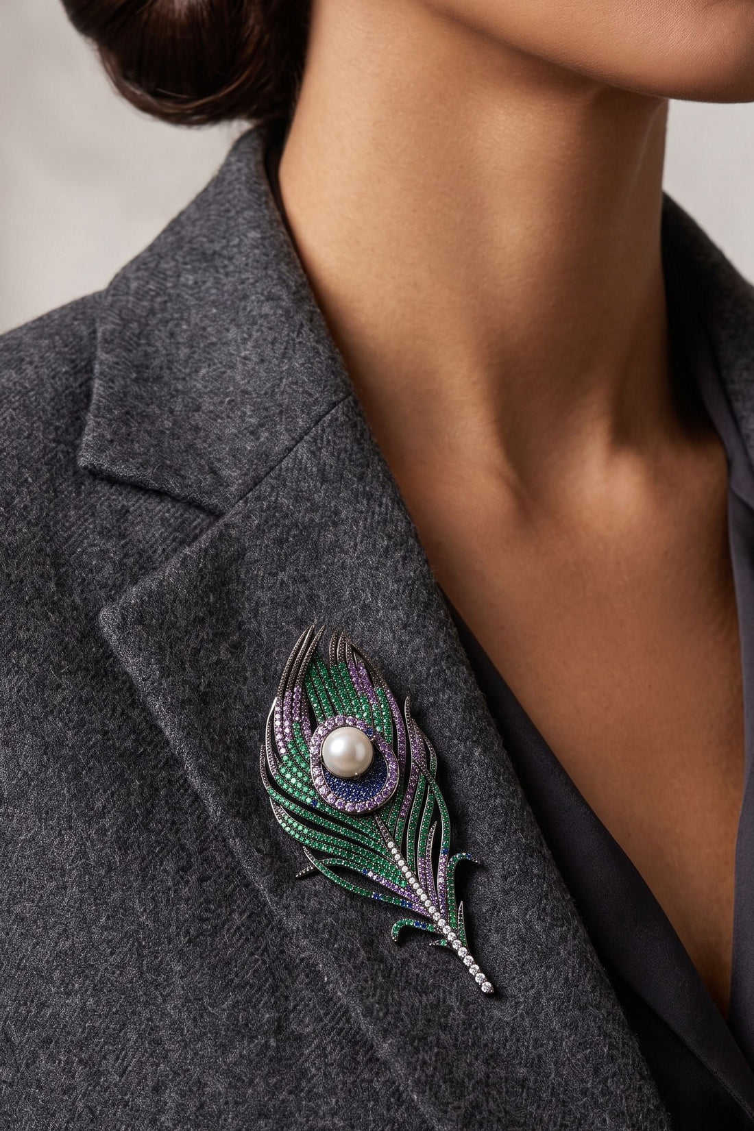 Peacock feather pearl brooch pinned on dark gray blazer, pearl center with green accents