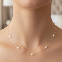 Natural pearl station necklace on a white gold chain, close-up on neckline
