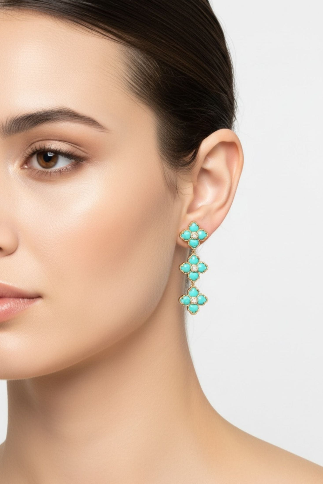 Turquoise enamel flower drop earrings on gold-tone hook, close-up on ear