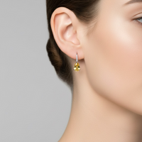 Teardrop earrings with yellow topaz dangling from a woman's ear
