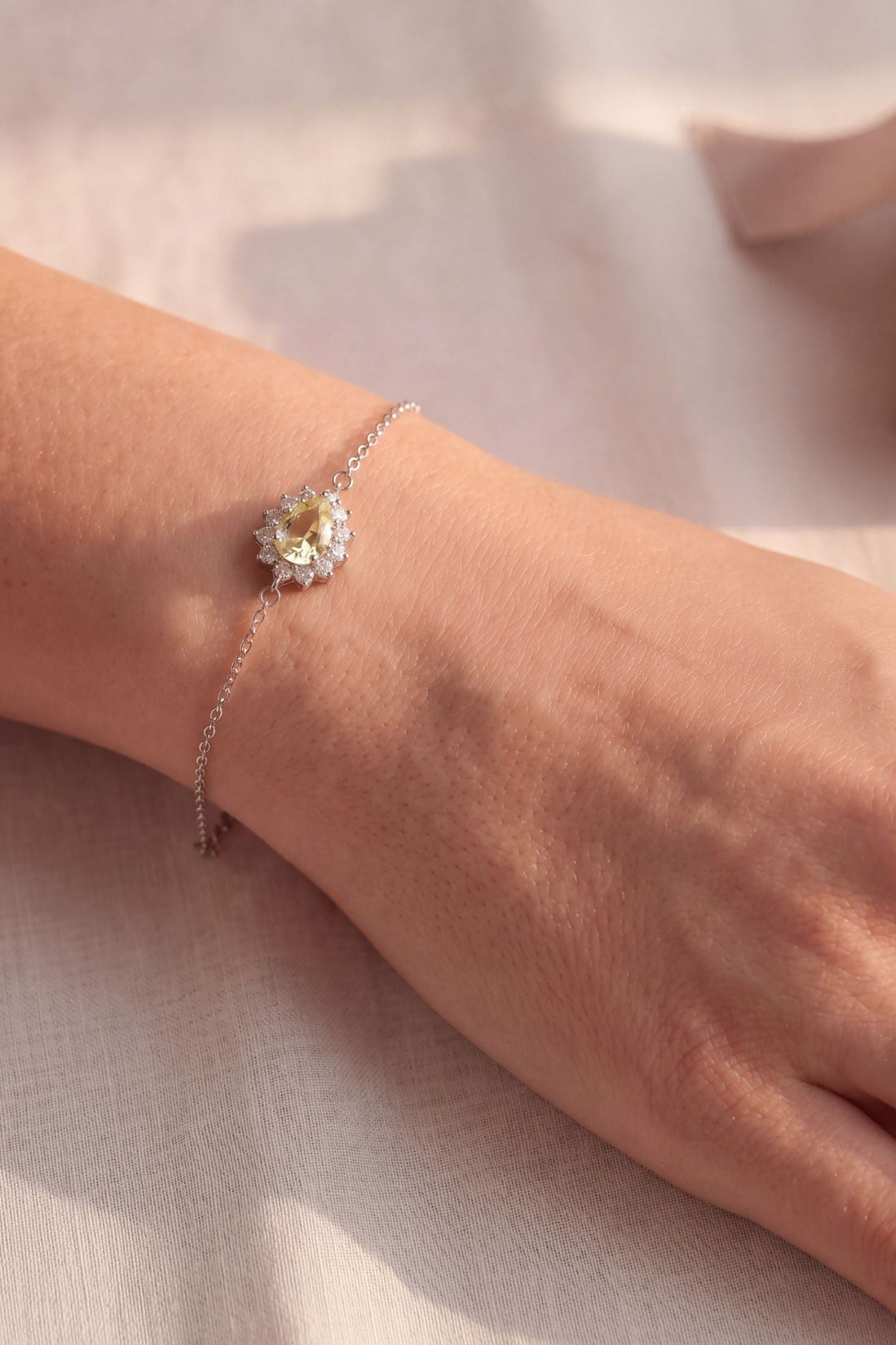Silver bracelet with small oval yellow gemstone on a fine chain