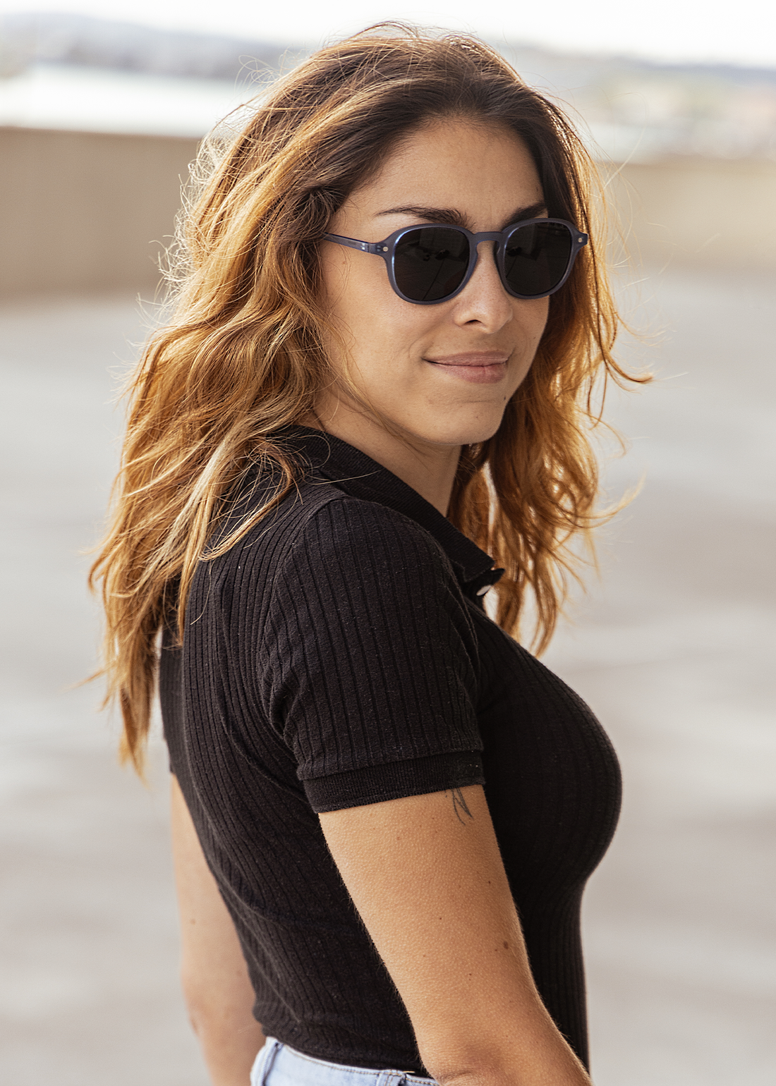 Round dark sunglasses on a person with a blue frame