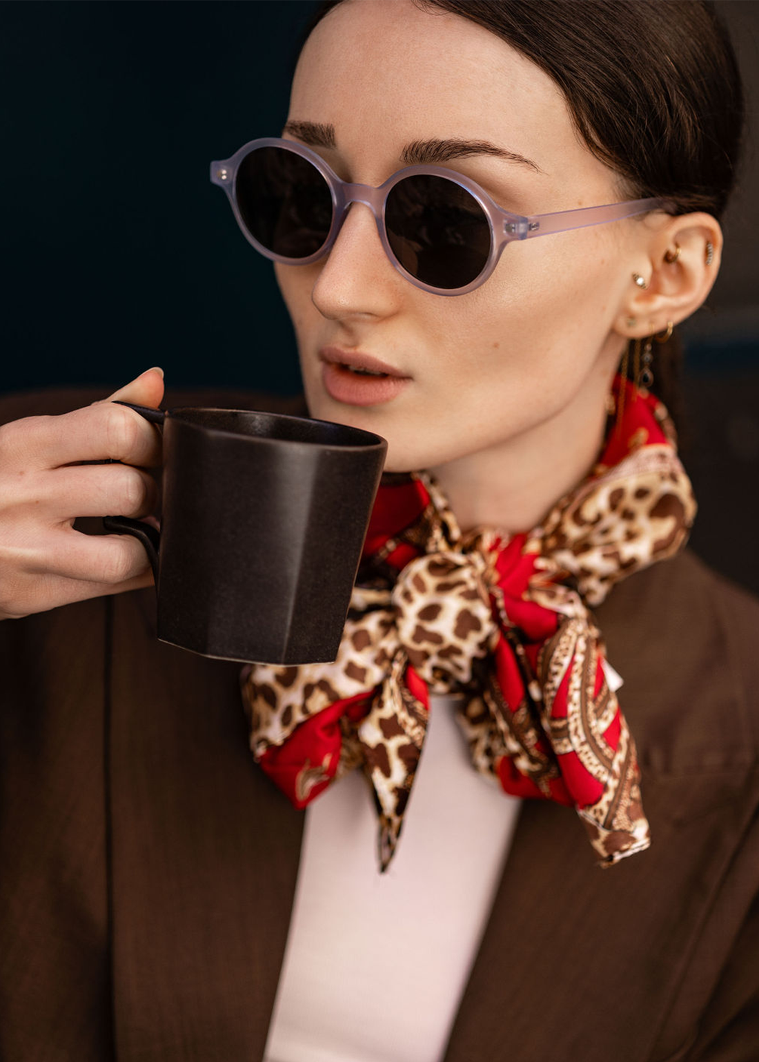 Woman wearing round sunglasses with dark lenses and light blue frames
