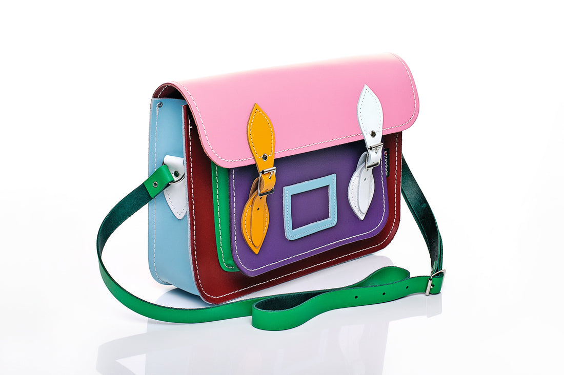 Multicolor leather satchel with pink flap, side view showing buckles and green shoulder strap