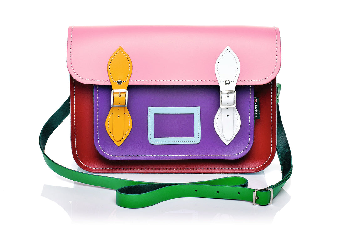 Pink leather satchel with flap, multicolor panels, yellow/white buckles, green strap