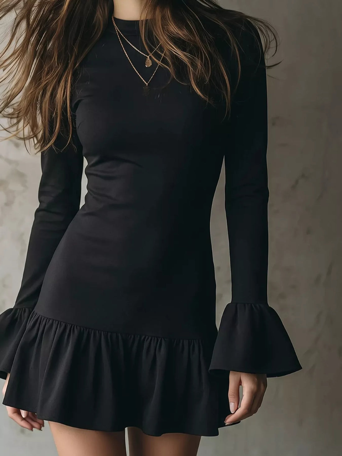 Black long-sleeve mini dress with ruffle hem and flared bell cuffs, close-up